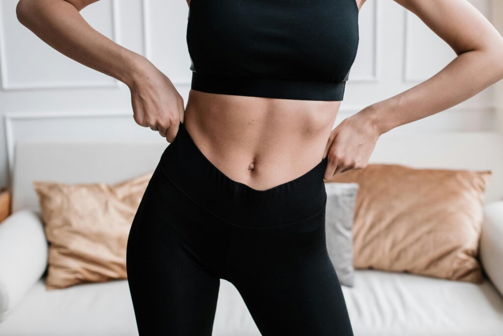 Close-up of a woman in activewear adjusting her pants in a stylish living room.